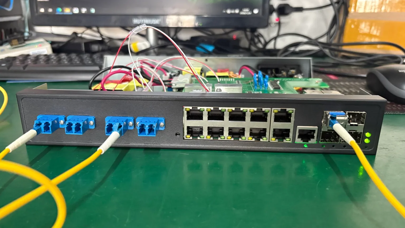 An open networking switch connected to fiber cables on an electronics testing workbench