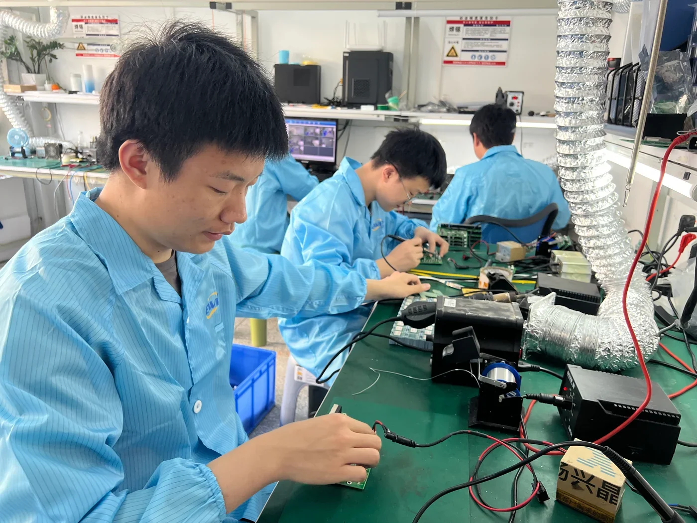 EWIND technicians working on network equipment circuit boards at an electronics workbench